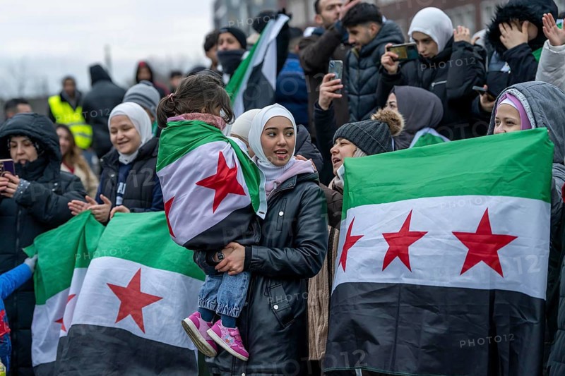 Syrian woman celebrate the end of the Assad regime after the change of power in Syria at a rally on the square in front of the main railway station in Duisburg, North Rhine-Westphalia, Germany