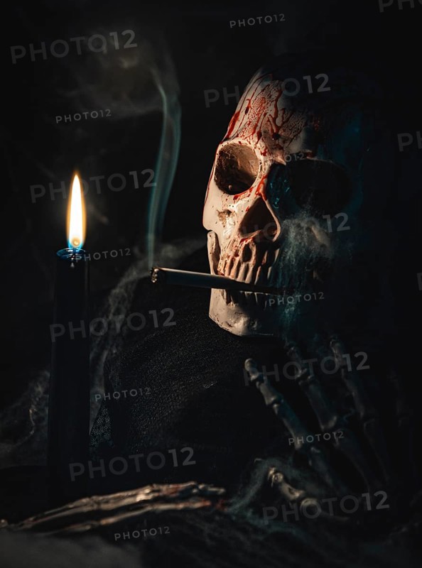 Bloodstained skull with cigarette and smoke next to a burning candle