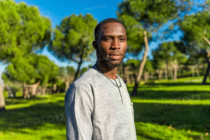 Portrait of a young african man from senegal wearing traditional clothing in a park, representing senegalese culture and muslim traditions