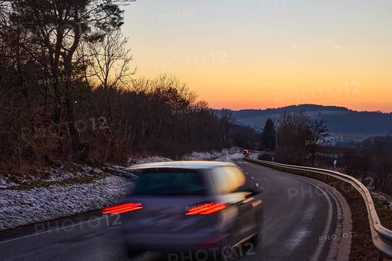 Country road, crash barrier, delineator, car, vehicle, brake light, reflector, motion blur, light traces, sunset, sunset, cloudless, hilly landscape, trees, federal road B421, Dreis-Brück, Eifel, Vulkaneifel district, Rhineland-Palatinate, Germany