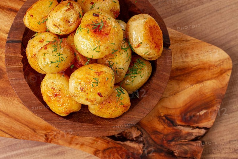 Baked new potatoes, with butter and dill, on a wooden plate, homely, rustic, no people