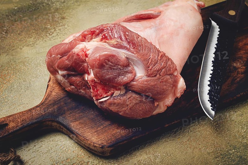 Raw pork knuckle, on a wooden chopping board, close-up, top view, no people