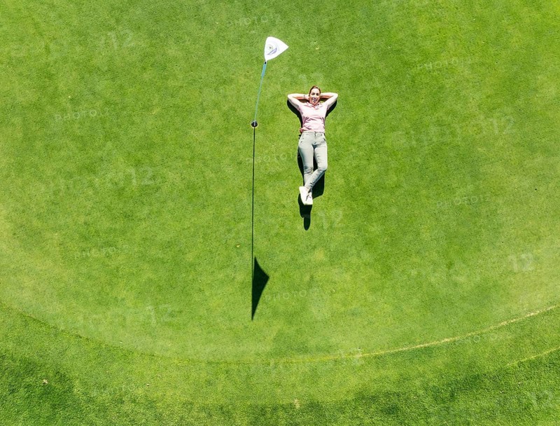 Woman lying on the green at the La Noria Golf Resort. Aerial view. Drone shot. Málaga province, Andalusia, Spain