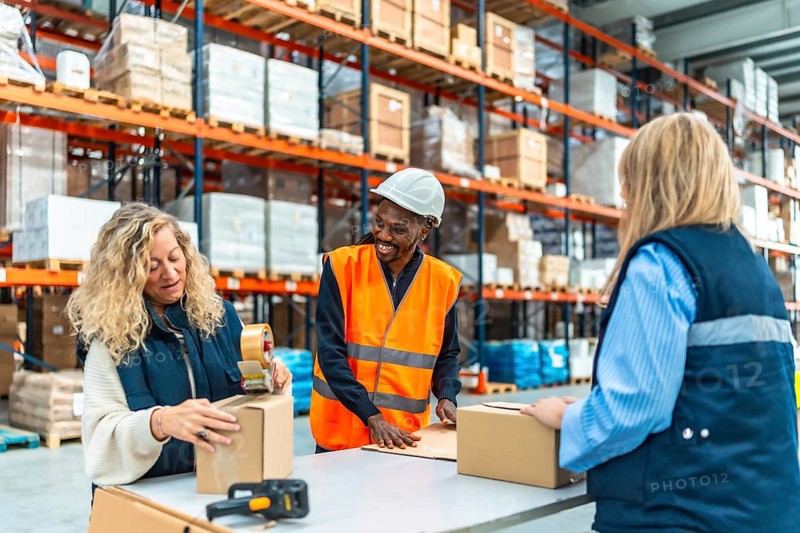 Multiracial male and females warehouse workers talking while preparing packages to deliver