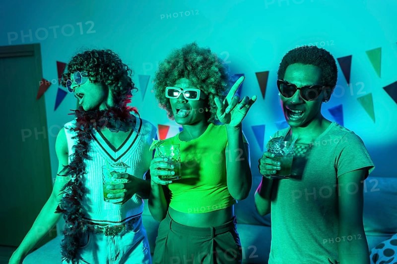 Multi-ethnic young students dancing and drinking alcohol during night party at home