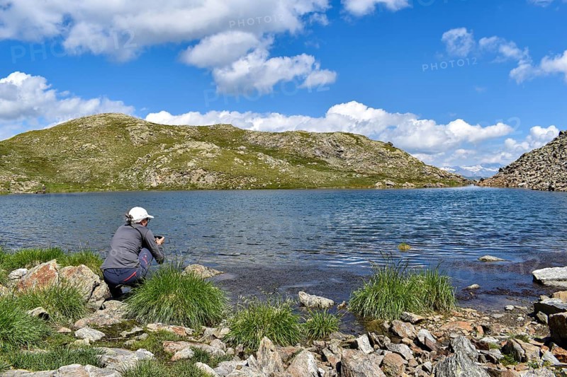 Woman photographing high alpine mountain lake at the Weiße Spitze, in the background the Großglockner, Deferegger Alps, Hohe Tauern, East Tyrol, Austria