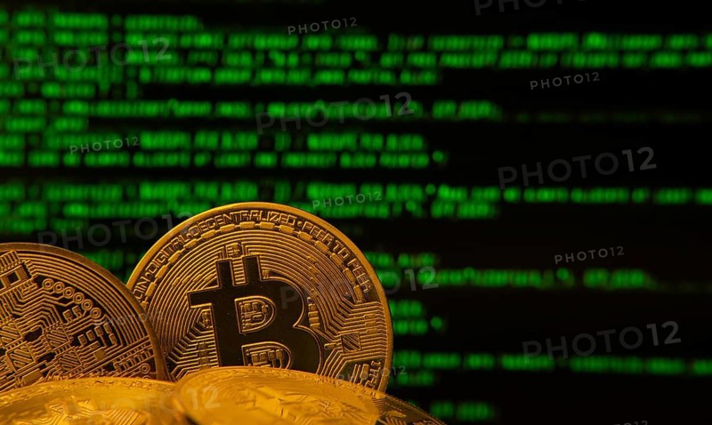 Golden bitcoins in front of green digital code, symbolizing cryptocurrency and technology