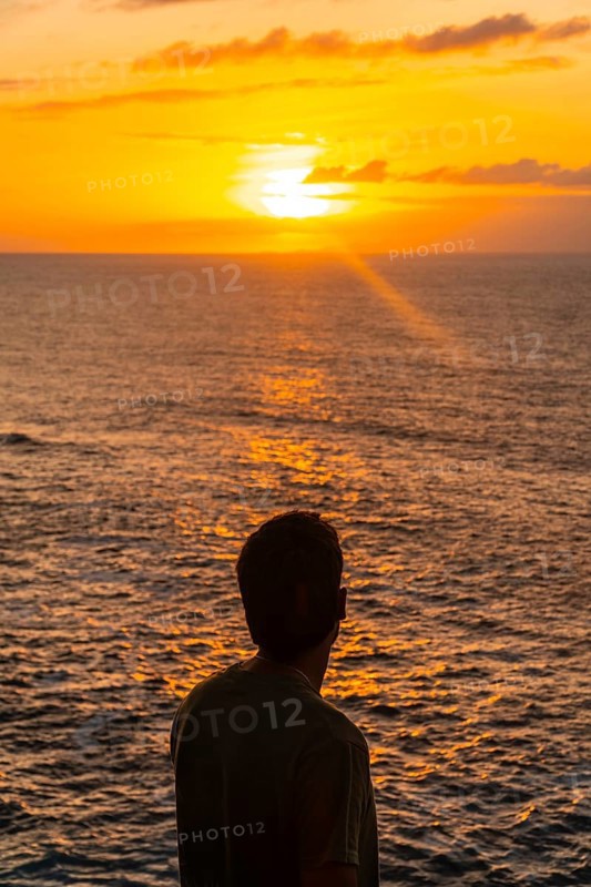 Silhouette of tourist contemplating beautiful golden sunset over atlantic ocean in agaete, gran canaria, canary islands, spain