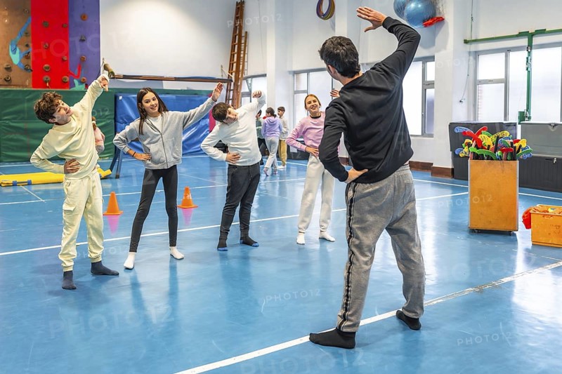 Students and teacher practicing stretching exercises during physical education class in a school gymnasium