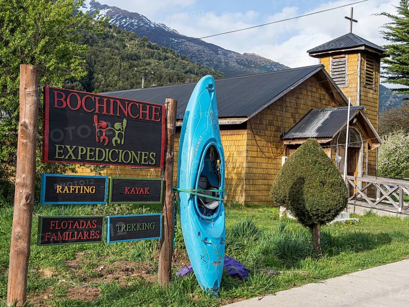 Signpost of tour operator for rafting, kayaking, trekking, next to wooden church, village Futaleufu, Chile