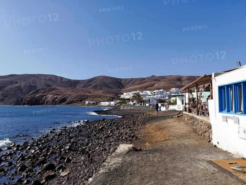 Black lava beach, white houses, fish restaurant, coastline, fishing village Playa Quemada, Yaiza, Lanzarote, Spain