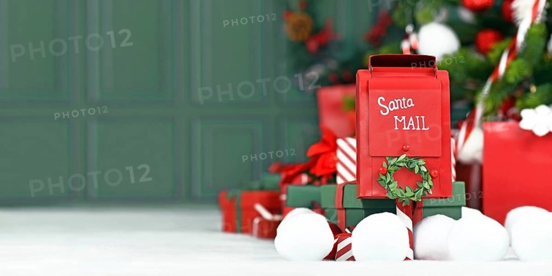 Christmas banner with red santa mail box in front of tree with green background with copy space