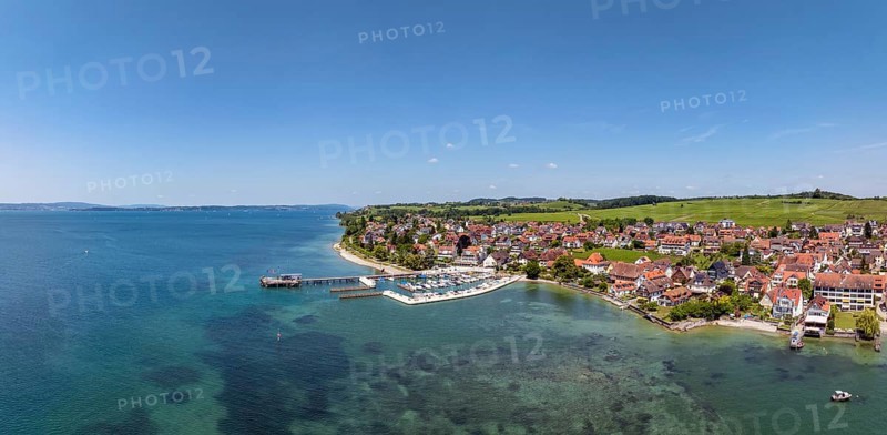 Luftbild, Panorama von der Bodenseegemeinde Hagnau, Winzerdorf und beliebter Ferienort am Bodensee, dahinter Rebhänge, auf denen hauptsächlich die Weinsorten Müller Thurgau und Blauer Burgunder angebaut werden. Am Seeufer der am 23.Mai 2025 eingeweihte, neue Westhafen, Yachthafen mit der Schiffanlegestelle, Bodenseekreis, Baden-Württemberg, Deutschland