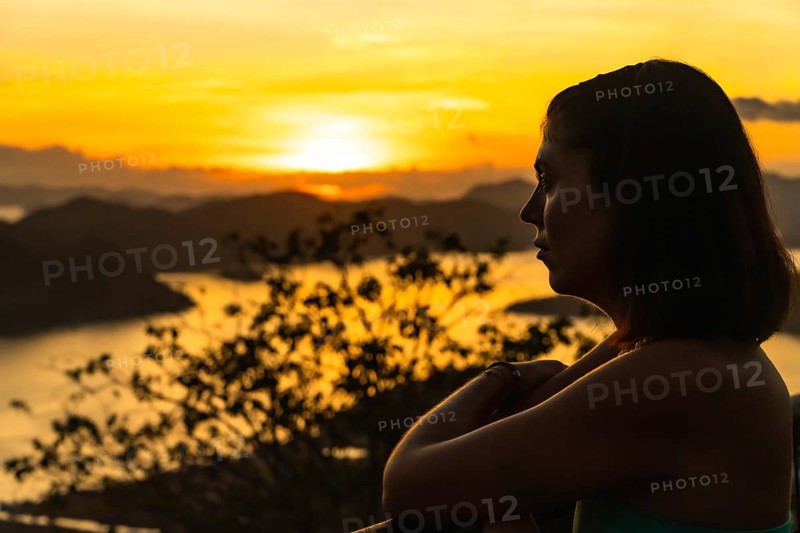 Silhouette of a tourist enjoying a beautiful golden sunset over coron island from mount tapyas viewpoint in busuanga, philippines