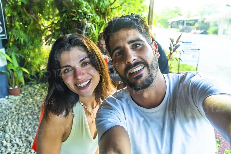 Young couple smiling and taking a selfie during their tropical vacation in siargao island, philippines