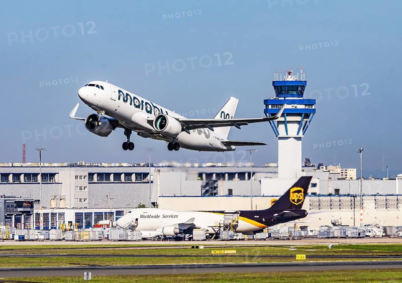Cologne Bonn Airport with tower. Aircraft taking off. Aircraft registration number ES-MBA, Marabou Stork Airlines, Airbus A320neo. Cologne, North Rhine-Westphalia, Germany