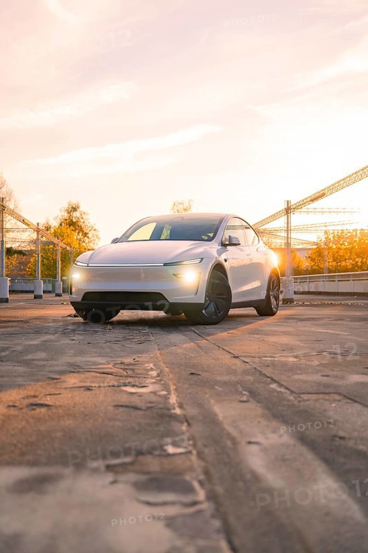 A white car in a city car park in the orange evening light, Tesla new Model Y Juniper, Nagold, Germany