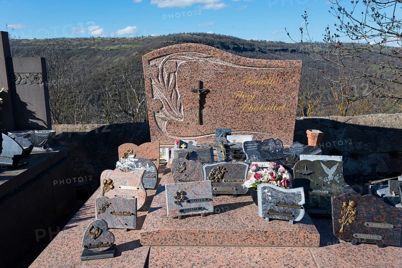 Grabsteine und Blumenschmuck auf einem Friedhof in einer hügeligen Landschaft mit einem christlichen Kreuz, Friedhof, Léotoing, Leotoing, Haute-Loire, Auvergne-Rhône-Alpes, Auvergne-Rhone-Alpes, Frankreich