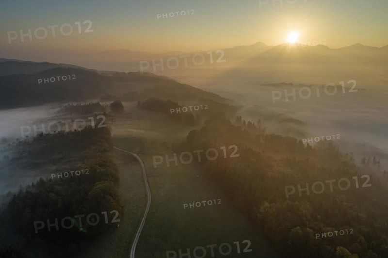 Aerial view of a mountain landscape over clouds, fog, sunrise, backlight, autumn, view of Kochler mountains, Alpine foothills, Bavaria, Germany