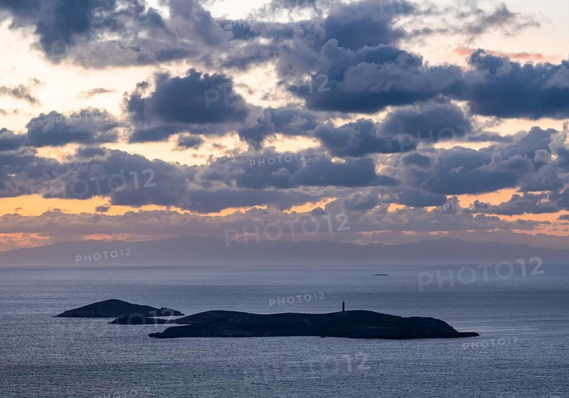 Nisos Gaidaros island with lighthouse in the sea at sunrise with dramatic clouds, Ermoupoli, Syros, Cyclades, Greece