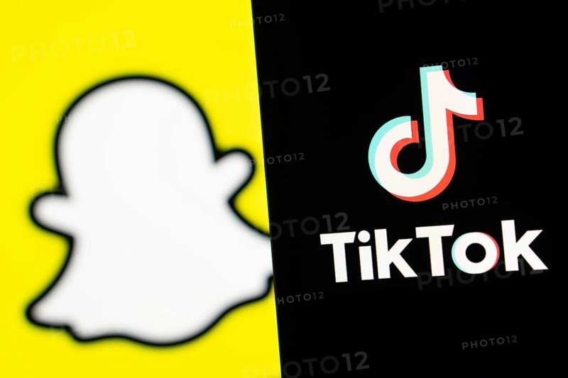Tiktok logo is seen on a smartphone and Snapchat in the background