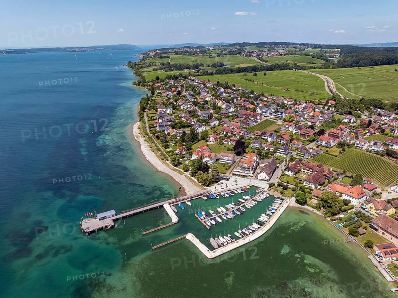 Luftbild von der Bodenseegemeinde Hagnau, Winzerdorf und beliebter Ferienort am Bodensee, dahinter Rebhänge, auf denen hauptsächlich die Weinsorten Müller Thurgau und Blauer Burgunder angebaut werden. Am Seeufer der am 23.Mai 2025 eingeweihte, neue Westhafen, Yachthafen mit der Schiffanlegestelle, Bodenseekreis, Baden-Württemberg, Deutschland
