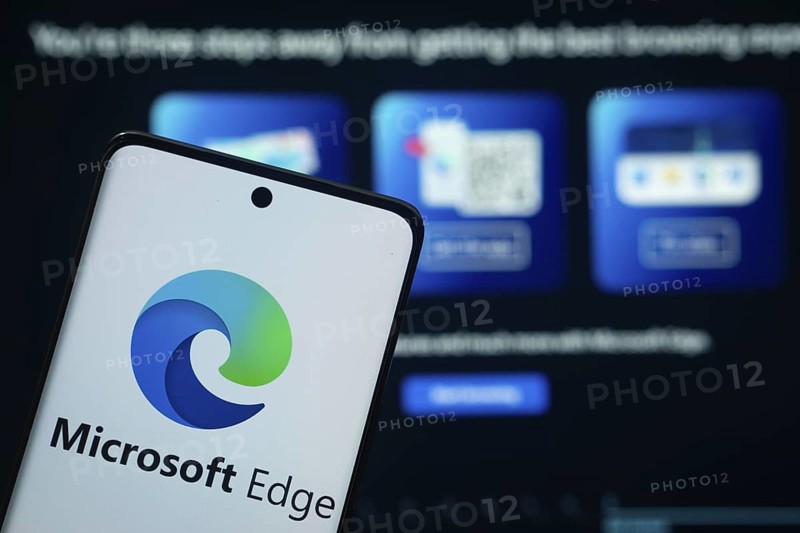 Dhaka, Bangladesh - 17 March 2025: The logo of the microsoft edge is displayed on a smartphone screen, and the website microsoft edge is visible on a computer screen in the background