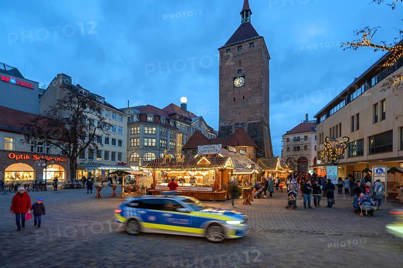 Christmas market, winter night at Jakobsplatz, behind White Tower, in front a passing police car, Nuremberg, Middle Franconia, Bavaria, Germany