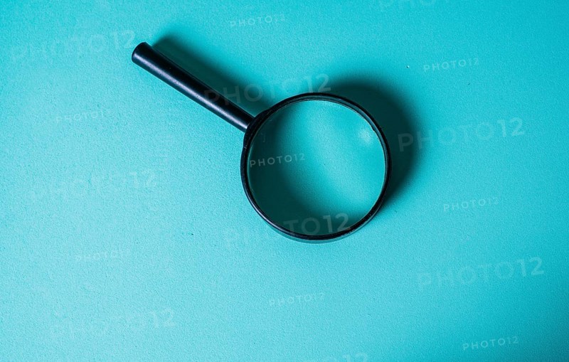 Magnifying Glass on Teal Background for Investigation Concept. CloseUp of Magnifying Glass for Search and Discovery Theme