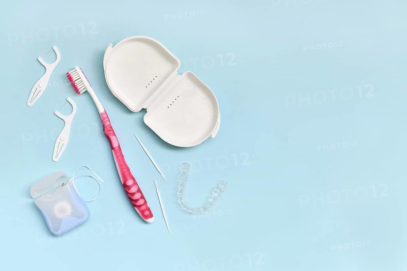 Top view of dental clear aligners, toothbrush, toothpicks and floss on blue background with copy space