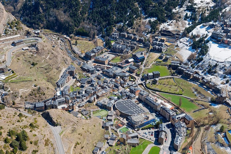 Blick auf eine kleine Stadt im Gebirgstal von Andorra mit verschneiten und grünen Flächen. Klar sichtbare Dächer und Straßen der Stadt, Mirador del Roc del Quer, Blick auf Canillo, Fürstentum Andorra, Pyrenäen
