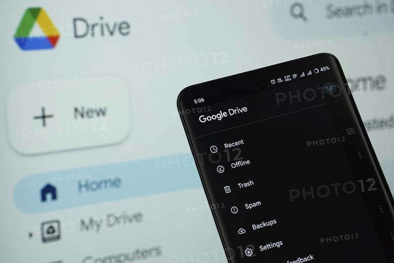 The app of the google drive is displayed on a smartphone screen, and the website google drive is visible on a computer screen in the background