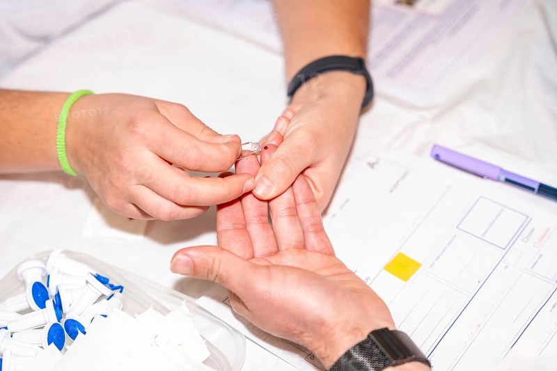 Close-up of a nurse checking blood sugar level by pricking the finger of a blood donor