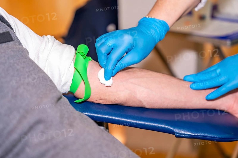 Nurse cleaning the area she is going to prick on the arm of a blood donor using a cotton swab