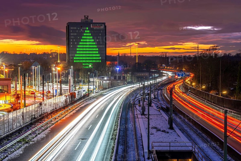 Autobahn A40, Ruhrschnellweg, between Essen and Mülheim an der Ruhr, evening traffic in winter, former, now vacant Stinnes high-rise building, at the Rhine-Ruhr Center, showing a green Christmas tree from illuminated windows at Christmas time, North Rhine-Westphalia, Germany