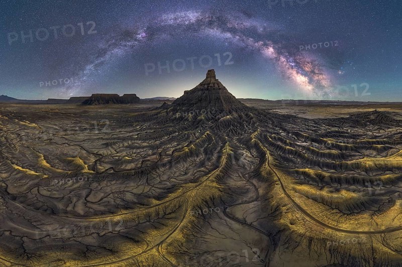 Stunning night scape of Utah sandstone desert under the Milky Way. The starry sky arches over textured terrain, creating a captivating natural scene filled with wonder