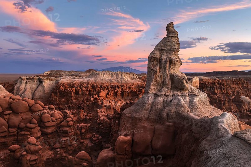 Majestic sandstone formations in Goblin Valley State Park, Utah, glow under a vibrant sunset sky, highlighting the park's unique geology and natural beauty