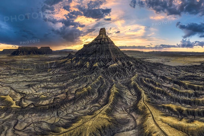 Dramatic sunset casts vibrant colors over the unique, eroded landscape of Factory Butte, Utah, highlighting the intricate patterns and textures of the badlands