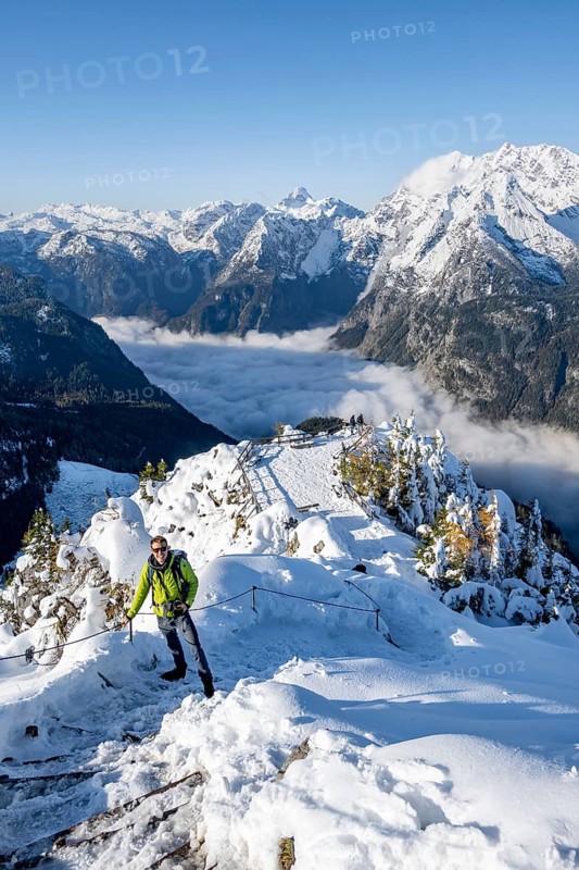 Tourist with camera on a hiking trail, Snow-covered summit of the Jenner with viewing platform in autumn, view of the sea of clouds and Watzmann, Berchtesgaden National Park, Berchtesgaden Alps, Schönau am Königssee, Berchtesgadener Land, Bavaria, Germany