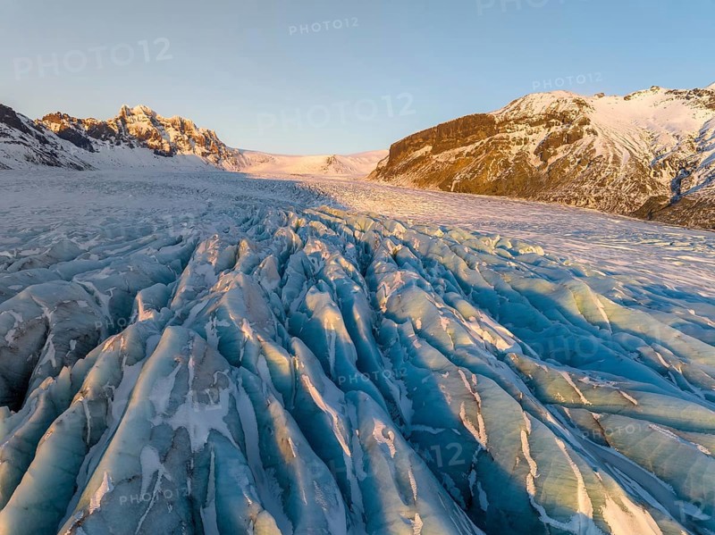 The stunning beauty of the Skaftafell Glacier during winter. The sunlight accentuates the rugged ice formations, creating a mesmerizing landscape of serene, icy grandeur