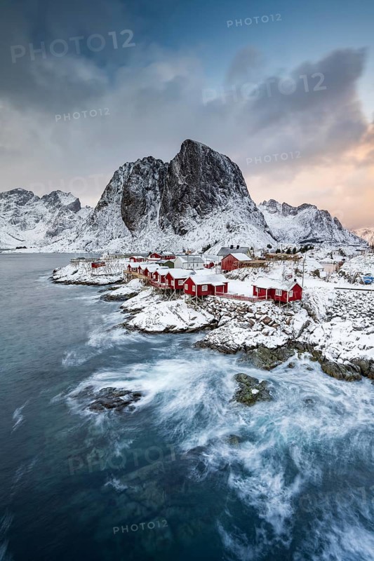 Rorbuer cabins of Hamnoy by the fjord, snowy mountains in the back, Hamnøy, Reine, Moskenesøya, Lofoten, Norway