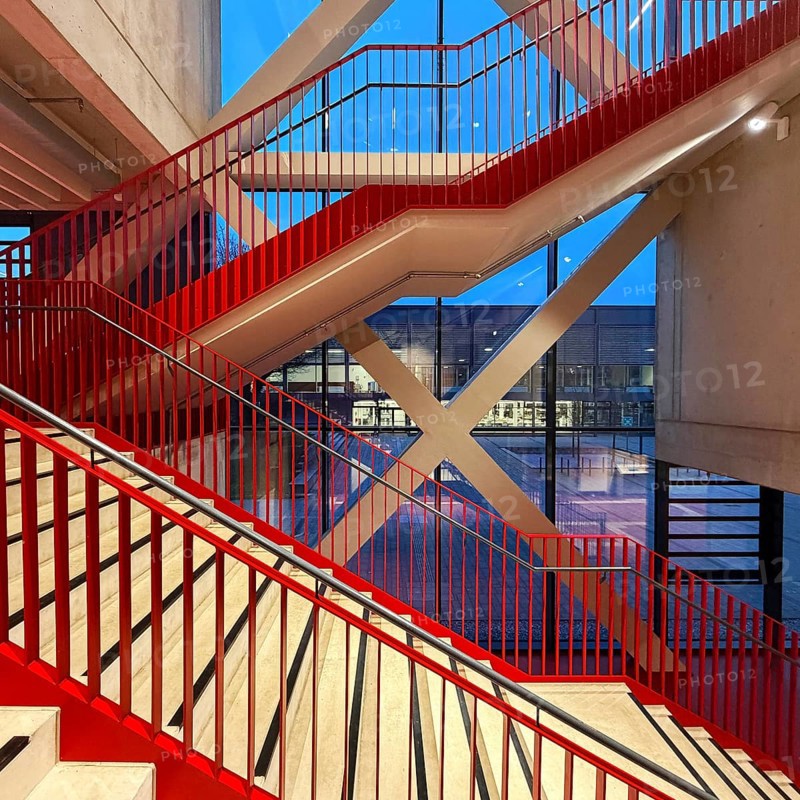 Staircase with signal red color scheme in seminar building H of Bochum University in the evening with a view of BlueBox Bochum, North Rhine-Westphalia, Germany
