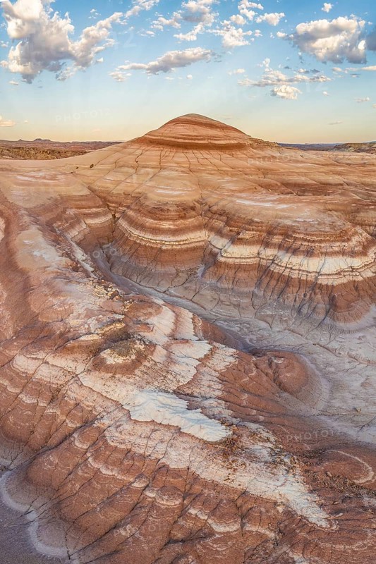 Stunning aerial shot capturing the intricate layers and rolling hills of bentonite clay in Utah's rugged landscape, highlighted by warm sunset hues