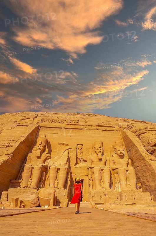 A European tourist in red dress walking towards the Abu Simbel Temple in southern Egypt in Nubia next to Lake Nasser. Temple of Pharaoh Ramses II, travel lifestyle