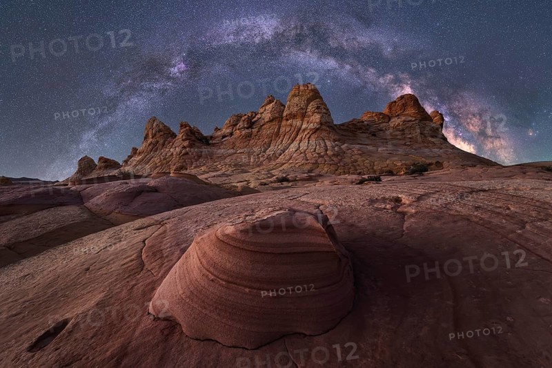 An awe inspiring view of the Milky Way galaxy illuminating the night sky above a rugged desert landscape with striking rock formations in Coyote Buttes, creating a breathtaking celestial scene