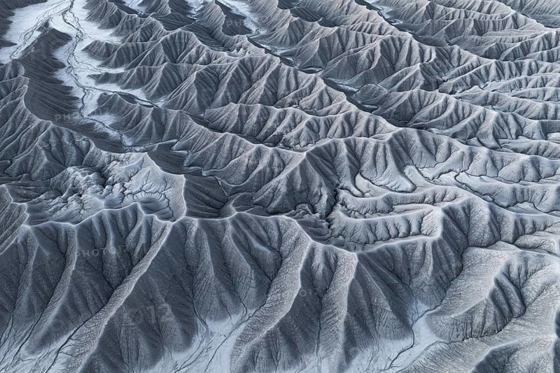 Captivating aerial shot capturing the intricate and rugged landscape of Caineville Mesa, near Hanksville, Utah, showcasing a tapestry of eroded rock formations and drainage patterns