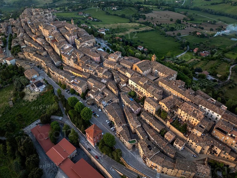 Aerial view of Treia, Italy, highlighting its remarkable medieval architecture nestled amid lush fields. This panorama captures the unique layout of the historic town