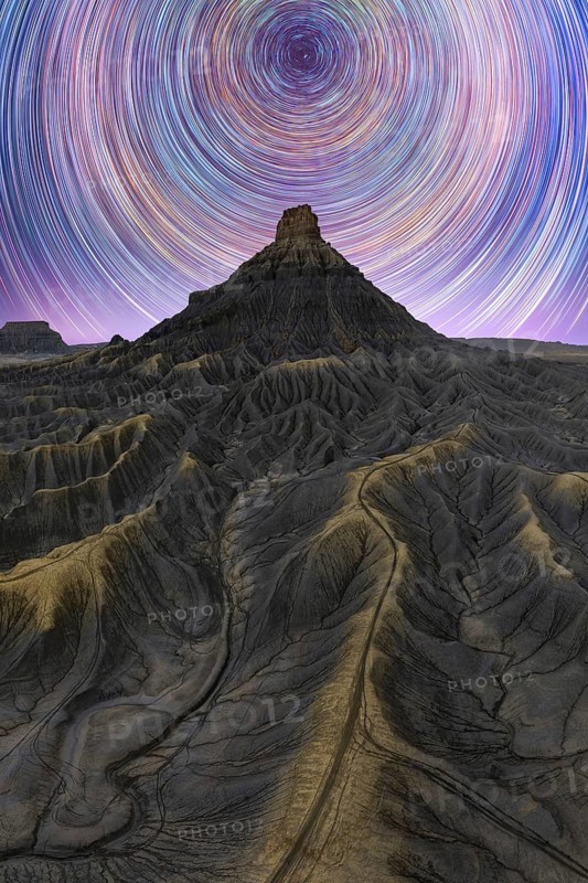 Stunning night view of the Milky way over Utah sandstone desert, showcasing star trails in a clear sky. The rugged terrain adds to the majestic landscape beauty