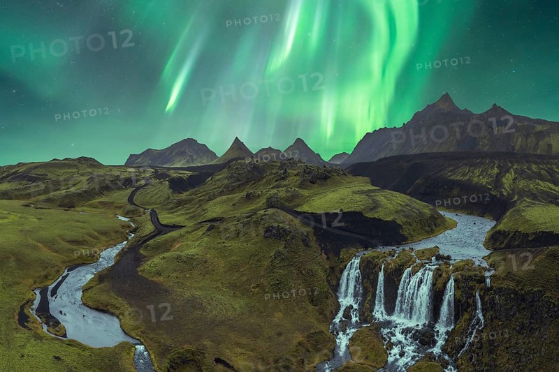 The breathtaking Northern Lights illuminate Iceland's dramatic terrain, featuring stunning mountains, waterfalls, and winding rivers