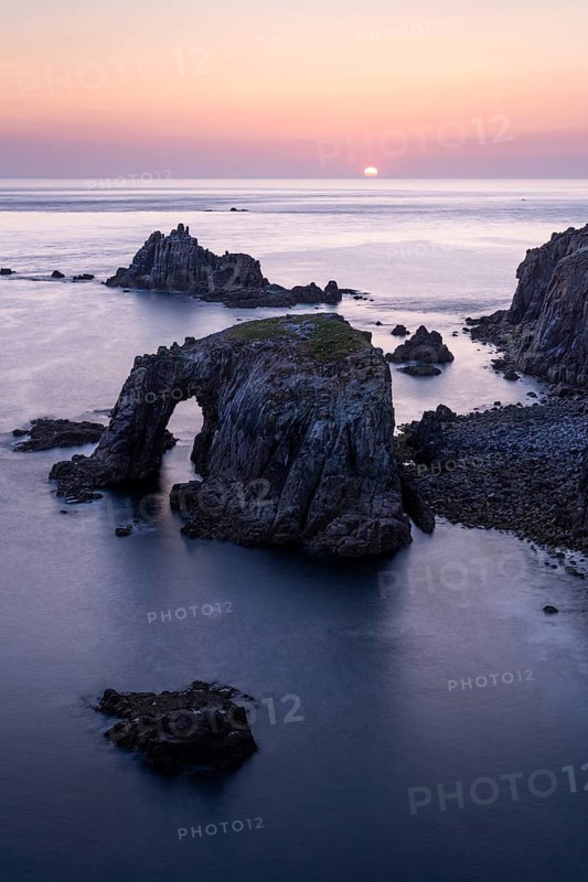 Coastal landscape at Land's End. The Enys Dodnan Arch with rock gate. In the evening at sunset. Long exposure. Land's End, Penzance, Cornwall, England, Great Britain